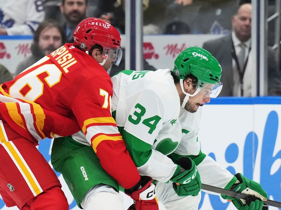 Martin Pospíšil (Calgary) sa snaží odstaviť od puku Austona Matthewsa (Toronto).