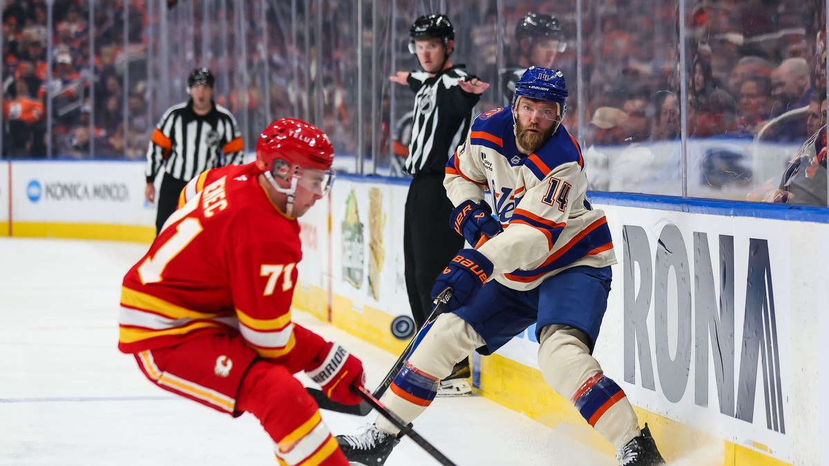 Hráč Edmontonu Oilers Mattias Ekholm (vpravo) strieľa cez Slováka Šimona Nemca z Calgary Flames v zápase zámorskej hokejovej NHL.