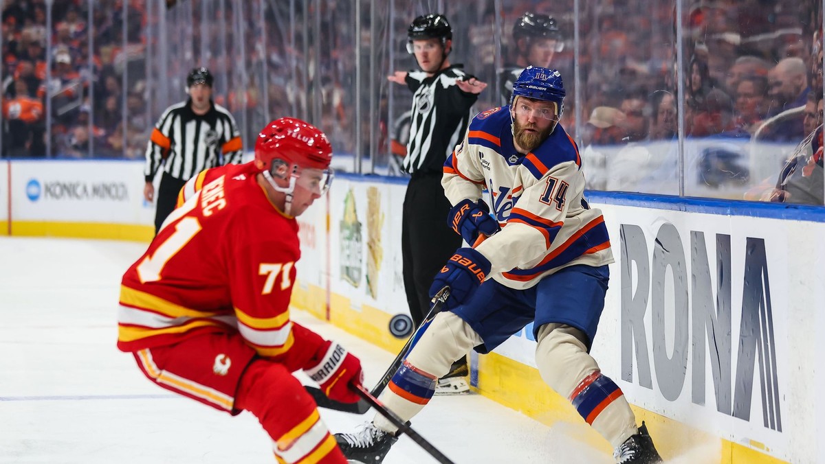 Hráč Edmontonu Oilers Mattias Ekholm (vpravo) strieľa cez Slováka Šimona Nemca z Calgary Flames v zápase zámorskej hokejovej NHL.