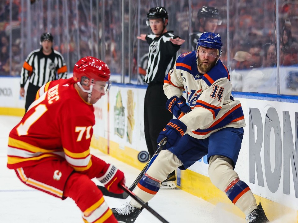 Hráč Edmontonu Oilers Mattias Ekholm (vpravo) strieľa cez Slováka Šimona Nemca z Calgary Flames v zápase zámorskej hokejovej NHL.