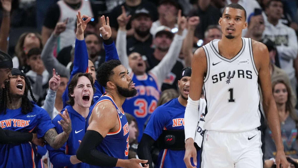 Hráči New York Knicks oslavujú koš, zatiaľ čo útočník San Antonio Spurs Victor Wembanyama (1) odchádza