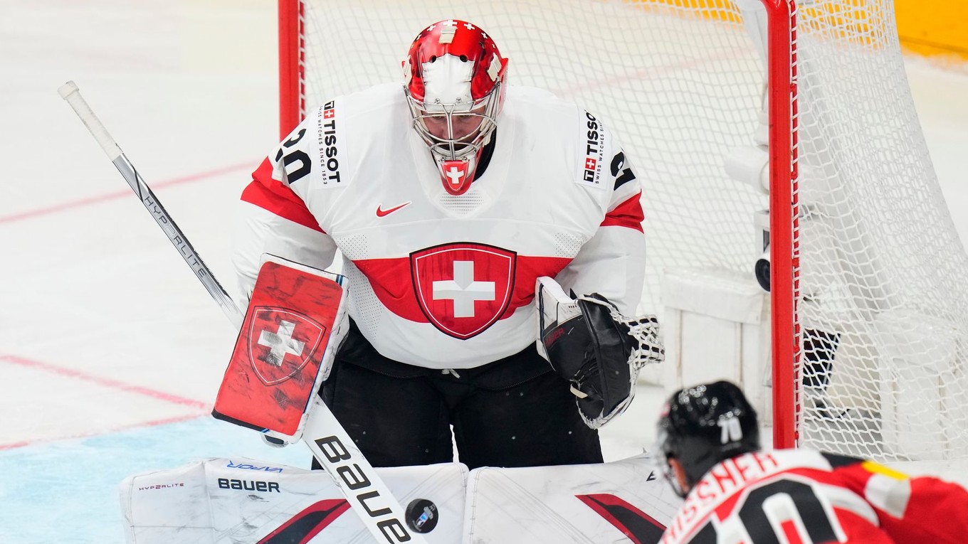 Švajčiarsky brankár Reto Berra zasahuje po strele rakúskeho hráča Benjamina Nissnera.
