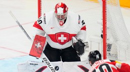 Švajčiarsky brankár Reto Berra zasahuje po strele rakúskeho hráča Benjamina Nissnera.