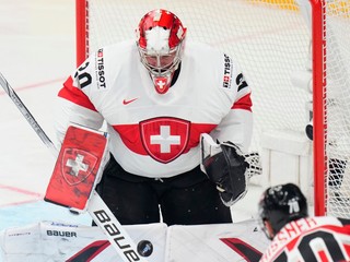 Švajčiarsky brankár Reto Berra zasahuje po strele rakúskeho hráča Benjamina Nissnera.