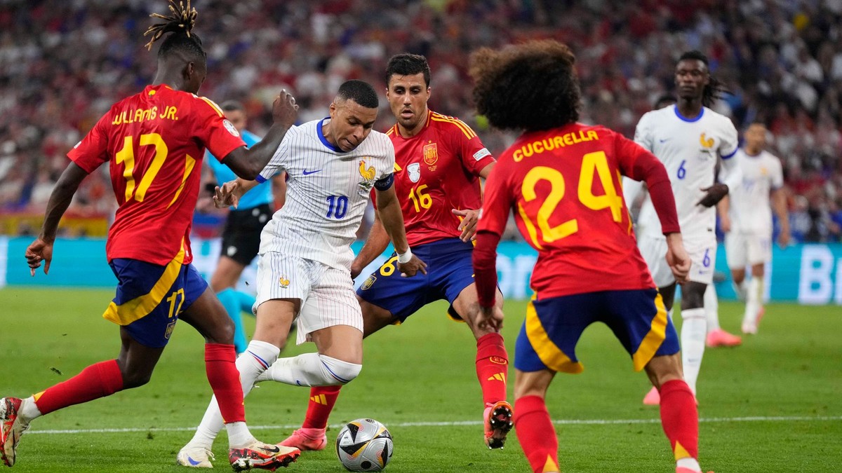 Kylian Mbappé z Francúzska je obkľúčený španielskymi hráčmi Nicom Williamsom (vľavo) a jeho spoluhráčmi Rodrim a Marcom Cucurellom počas semifinálového zápasu medzi Španielskom a Francúzskom na futbalovom turnaji EURO 2024.