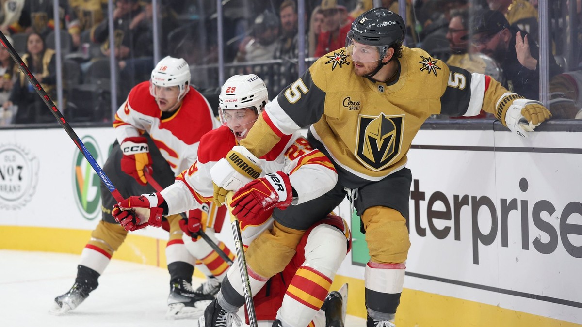 Slovenský hokejista v drese Calgary Flames Samuel Honzek (uprostred) a hráč Vegasu Jeremy Lauzon (vpravo) bojujú o puk.