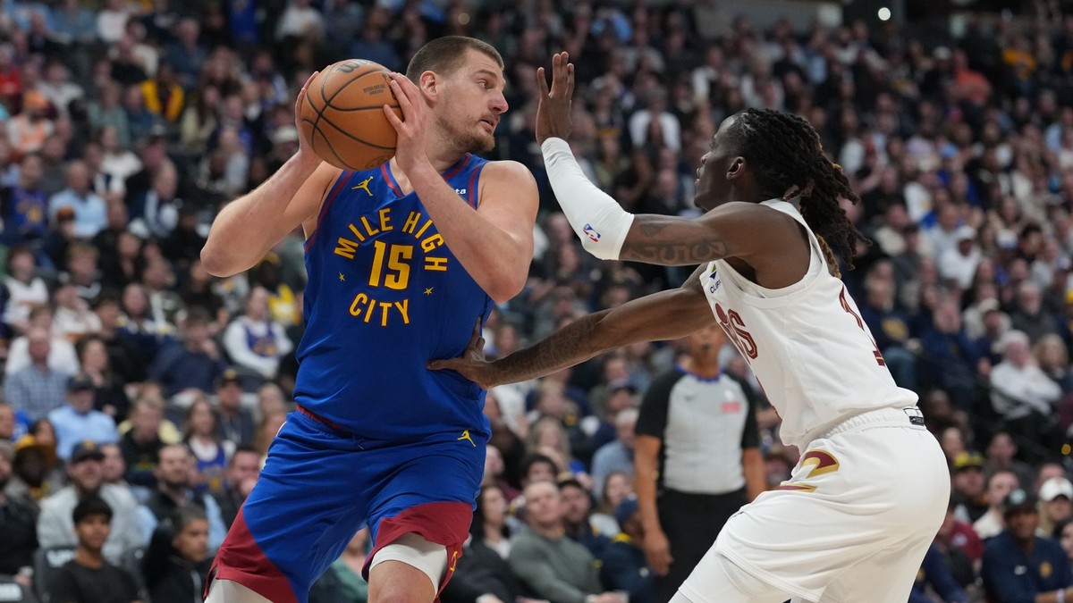 Center Denver Nuggets Nikola Jokić (vľavo) sa snaží prihrať loptu, zatiaľ čo ho bráni rozohrávač Cleveland Cavaliers Keon Ellis.