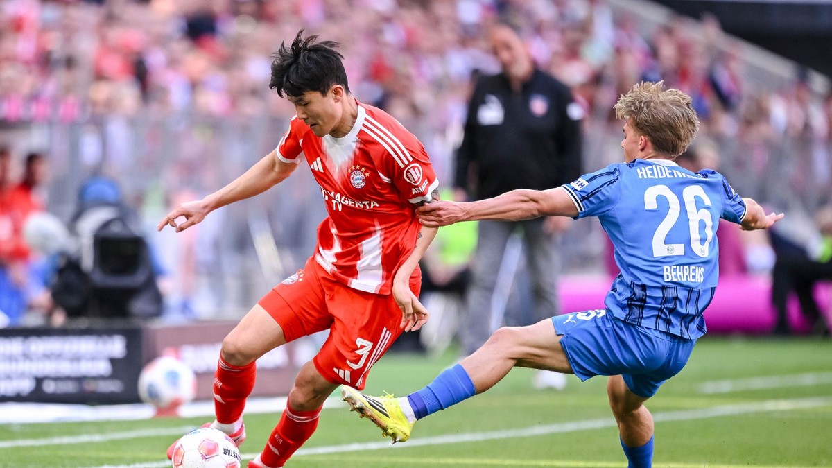 Futbalista Bayernu Kim Min-če (vľavo) a hráč Heidenheimu Hennes Behrens bojujú o loptu.