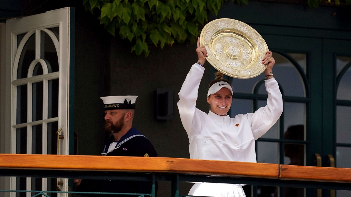 Češka Markéta Vondroušová prichádza na balkón s trofejou pre víťazku Wimbledonu.  