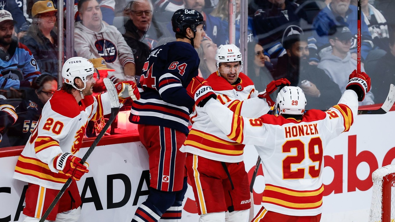 Blake Coleman, Mikael Backlund a Samuel Honzek oslavujú gól. 