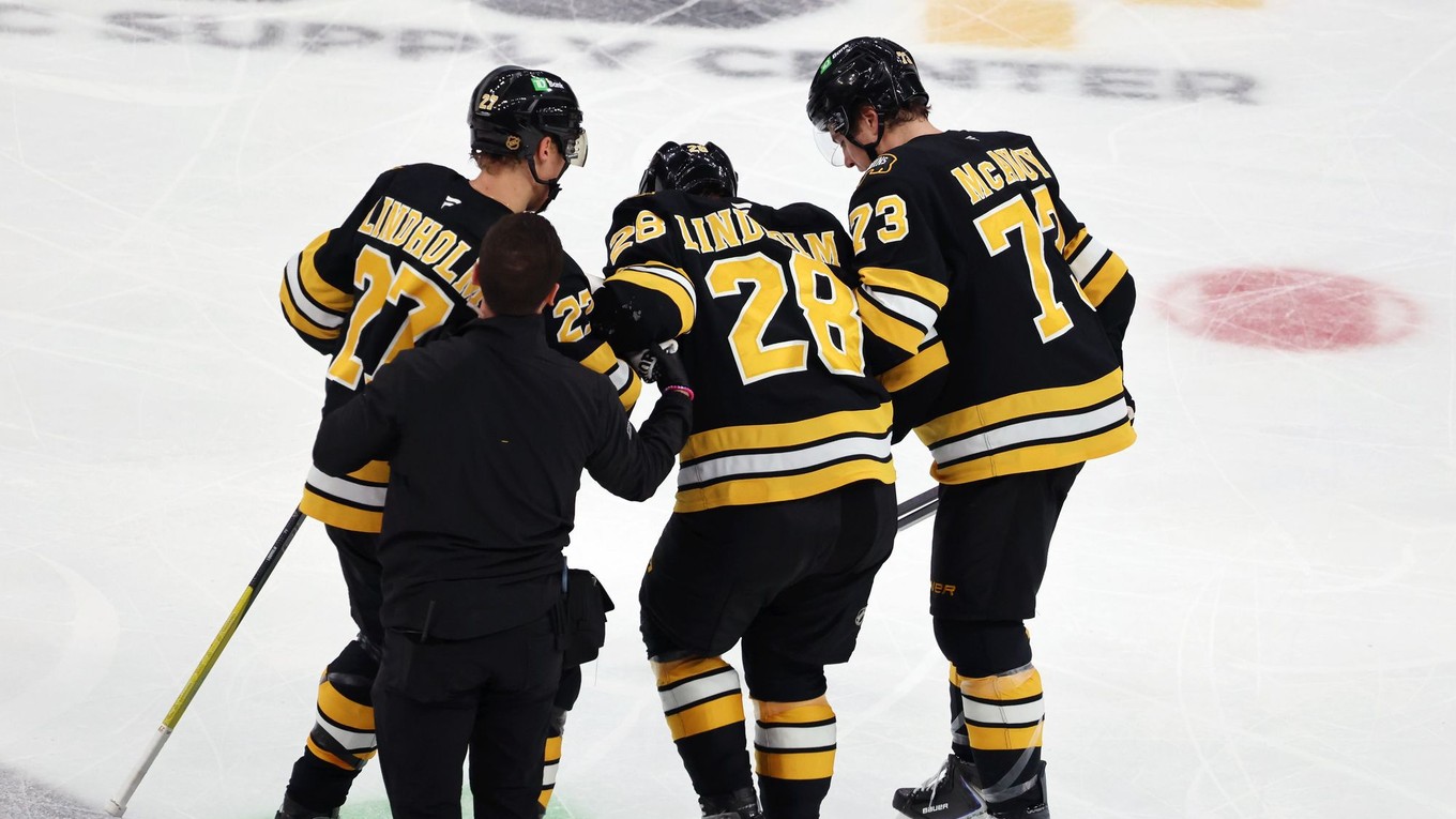 Hampus Lindholm a Charlie McAvoy pomáhajú Eliasovi Lindholmovi dostať sa z ľadu počas druhej tretiny zápasu proti tímu Buffalu.