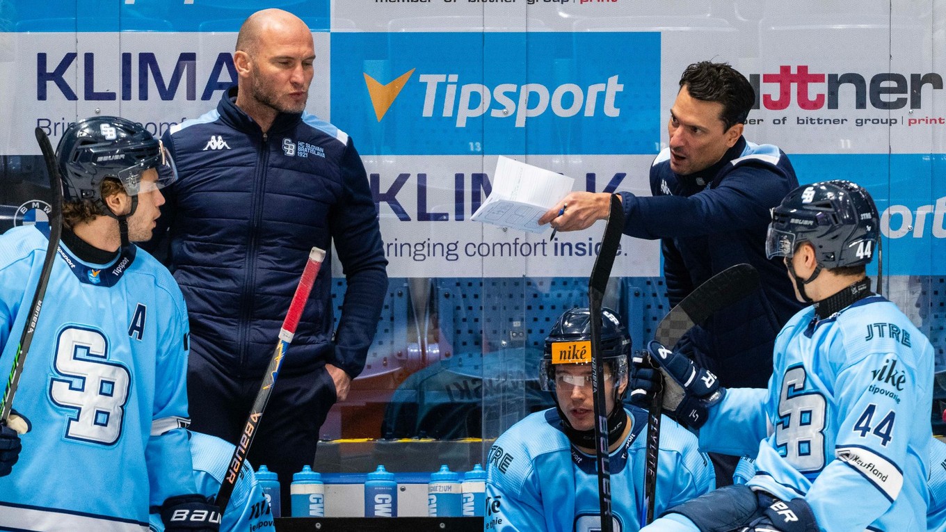 Tréner HC Slovan Bratislava Brad Tapper a vľavo asistent trénera Tomáš Surový spolu s hráčmi.