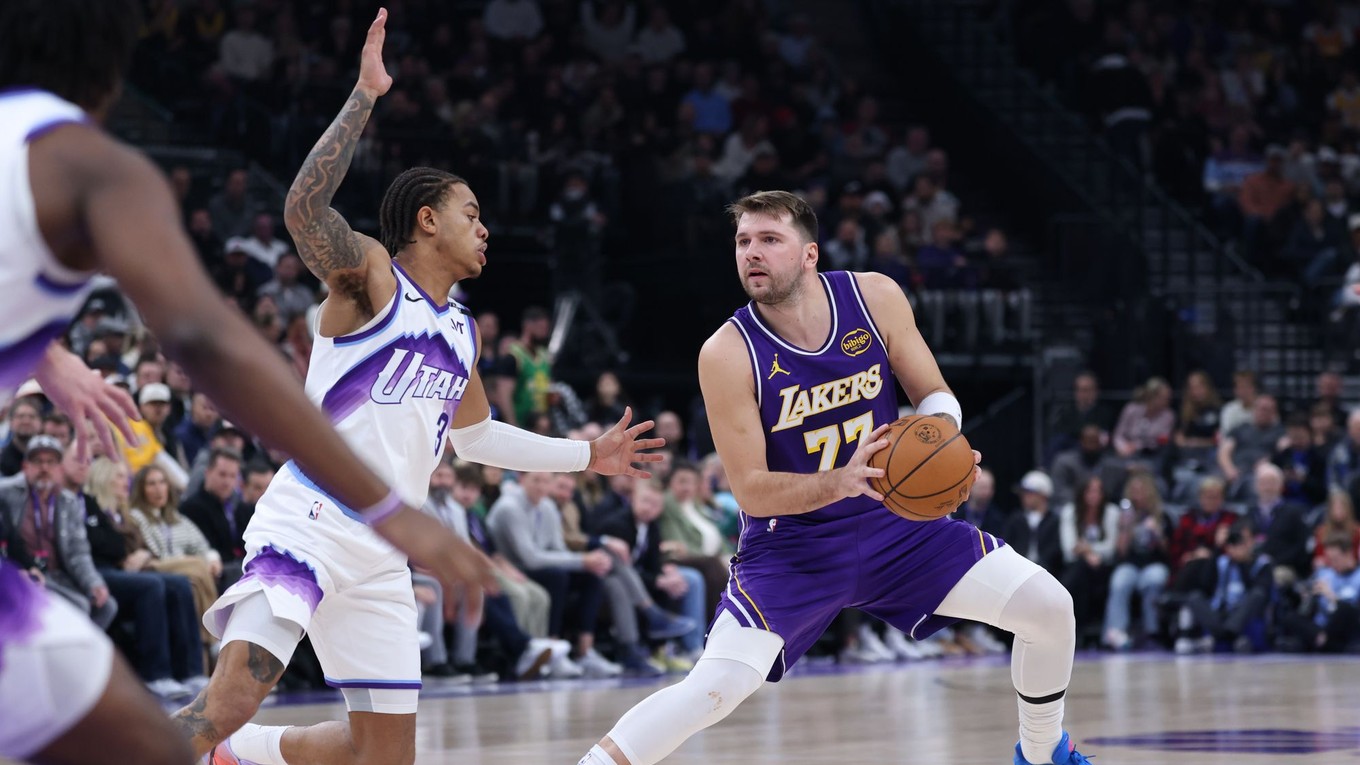 Rozohrávač Los Angeles Lakers Luka Dončić (77) s krokom kroku späť a strieľa, zatiaľ čo ho bráni rozohrávač Utah Jazz Keyonte George (vľavo).