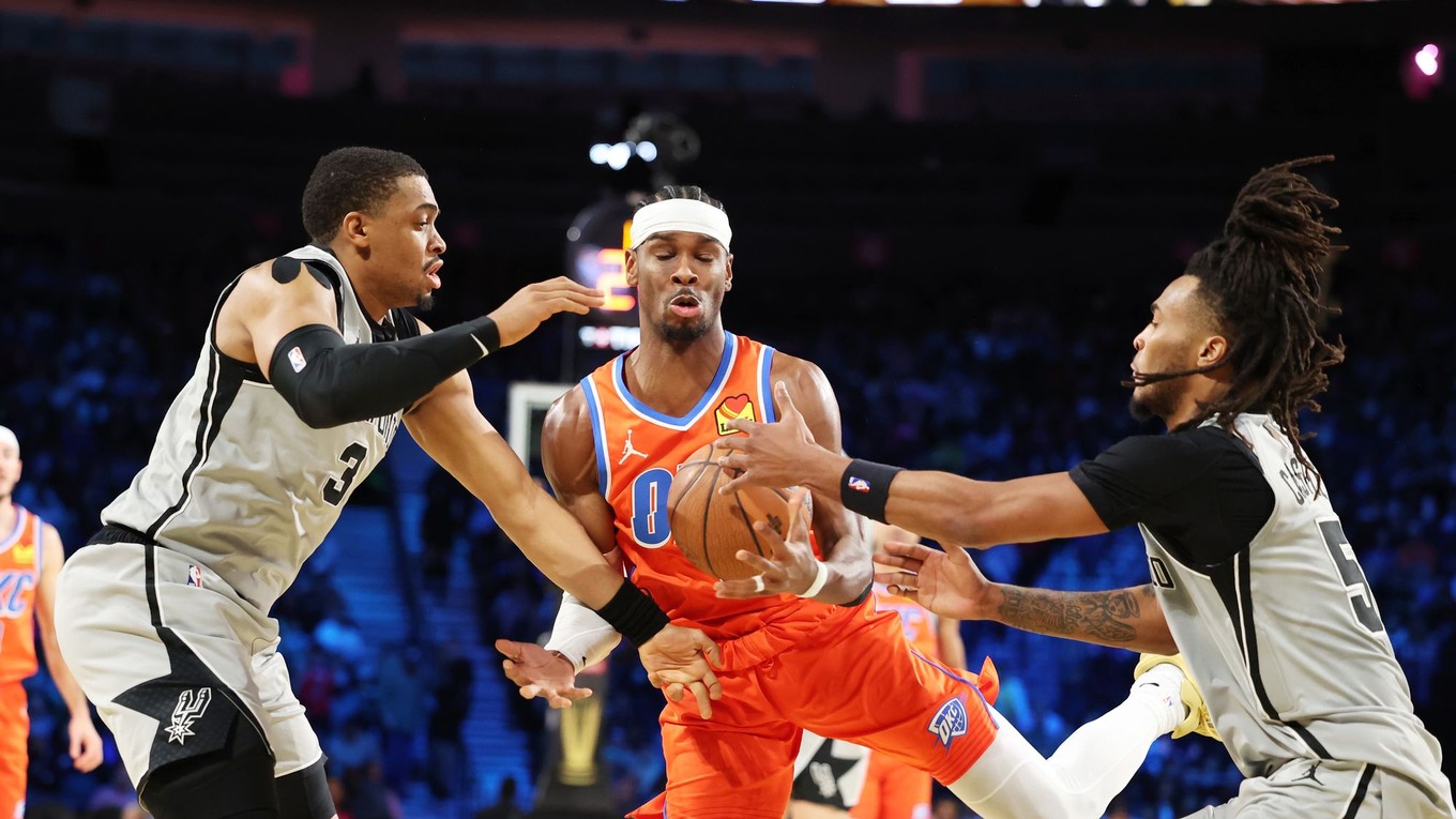 Rozohrávač Oklahoma City Thunder Gilgeous-Alexander v zápase NBA s hráčmi San Antonio Spurs Johnsonom (3) a Castlom (5).
