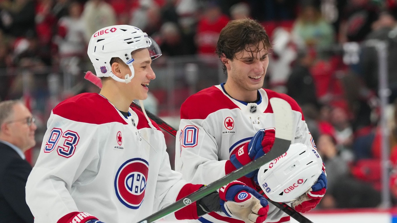 Vpravo slovenký útočník Juraj Slafkovský v drese Montrealu (20) a Ivan Demidov (93) oslavujú víťazstvo proti Caroline.