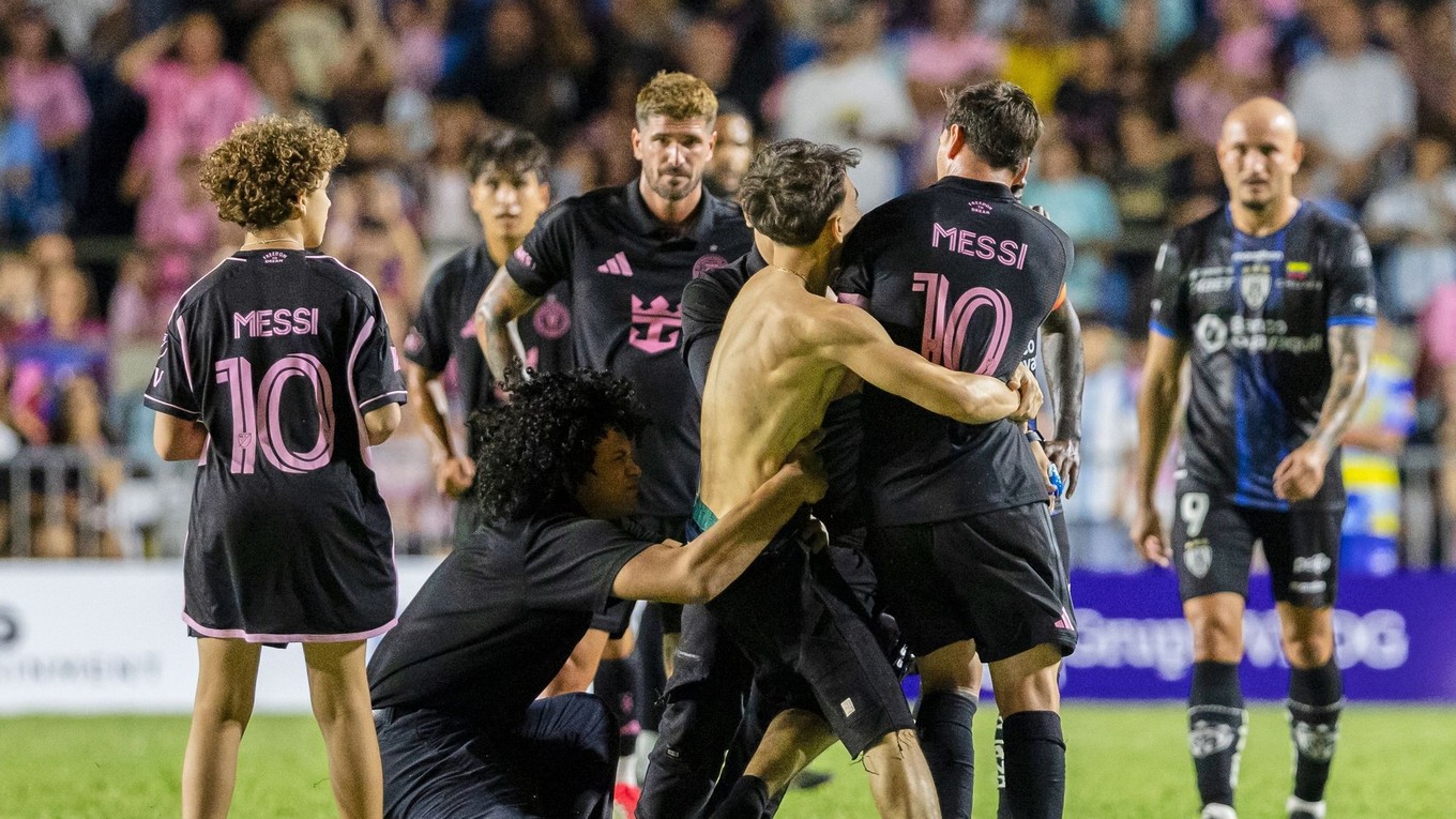 Fanúšik, ktorý sa dostal na ihrisko, chytá hráča Lionela Messiho z Interu Miami na konci prípravného futbalového zápasu.