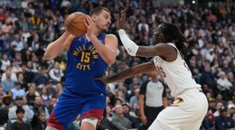 Center Denver Nuggets Nikola Jokić (vľavo) sa snaží prihrať loptu, zatiaľ čo ho bráni rozohrávač Cleveland Cavaliers Keon Ellis.