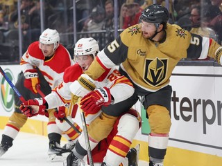 Slovenský hokejista v drese Calgary Flames Samuel Honzek (uprostred) a hráč Vegasu Jeremy Lauzon (vpravo) bojujú o puk.