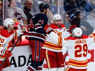 Blake Coleman, Mikael Backlund a Samuel Honzek oslavujú gól. 