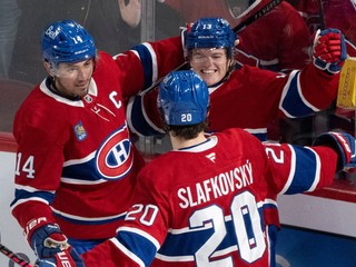Slovenský hokejista v drese Montrealu Juraj Slafkovský (20) a jeho spoluhráč Nick Suzuki (14) sa tešia z gólu, ktorý strelil Cole Caufield (13).