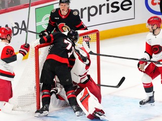 Center tímu Ottawa Senators Ridly Greig (71) narazil brankára tímu Carolina Hurricanes Frederika Andersena (vpravo v strede) do jeho brány.