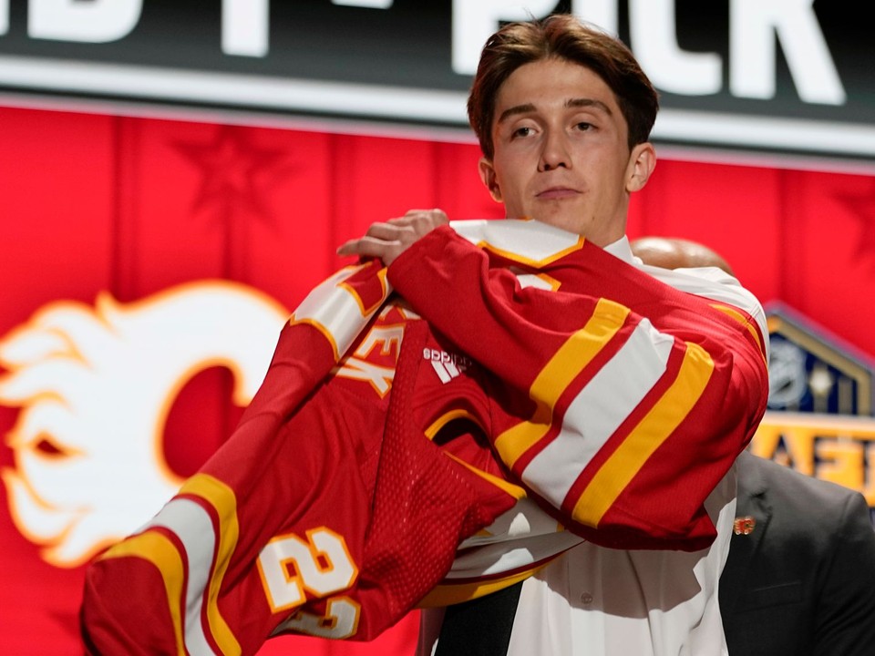 Samuel Honzek si oblieka dres Calgary Flames vo vstupnom drafte NHL 2023. 