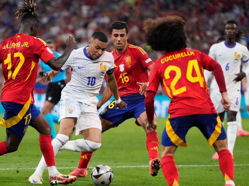 Kylian Mbappé z Francúzska je obkľúčený španielskymi hráčmi Nicom Williamsom (vľavo) a jeho spoluhráčmi Rodrim a Marcom Cucurellom počas semifinálového zápasu medzi Španielskom a Francúzskom na futbalovom turnaji EURO 2024.