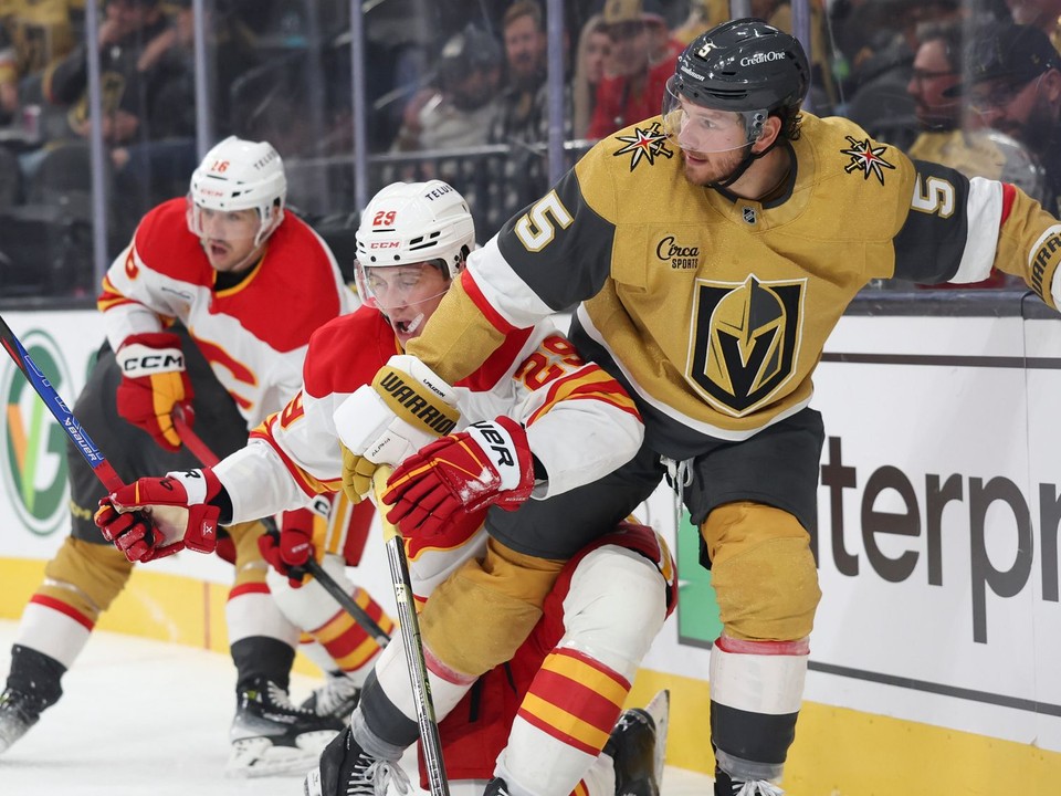 Slovenský hokejista v drese Calgary Flames Samuel Honzek (uprostred) a hráč Vegasu Jeremy Lauzon (vpravo) bojujú o puk.