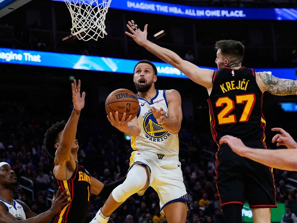Rozohrávač Golden State Warriors Stephen Curry (30) strieľa medzi krídelníkom Atlanty Johnsonom (1) a rozohrávačom Krejčím (27).