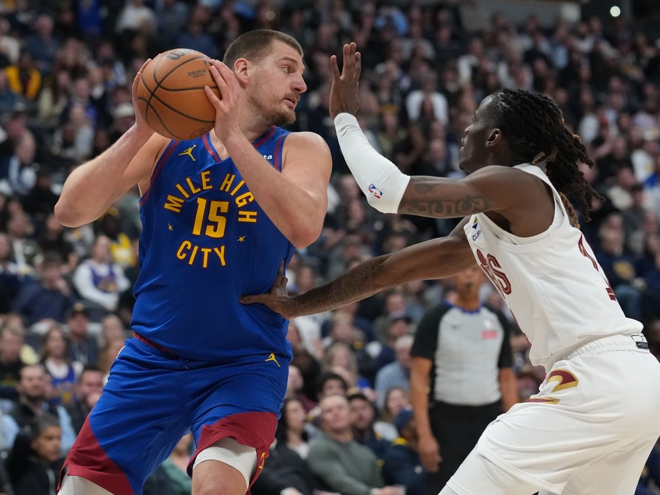 Center Denver Nuggets Nikola Jokić (vľavo) sa snaží prihrať loptu, zatiaľ čo ho bráni rozohrávač Cleveland Cavaliers Keon Ellis.