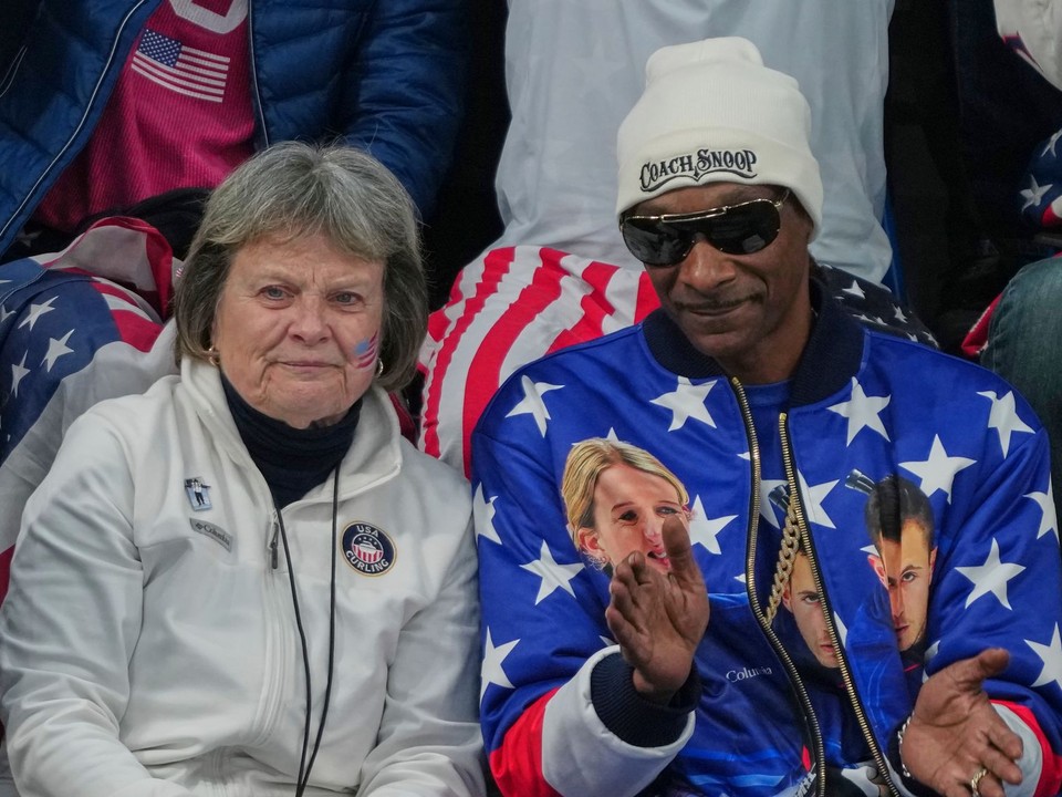 Snoop Dogg v hľadisku počas curlingového zápasu v spoločnosti mamy amerického curlera Koreyho Dropkina. 