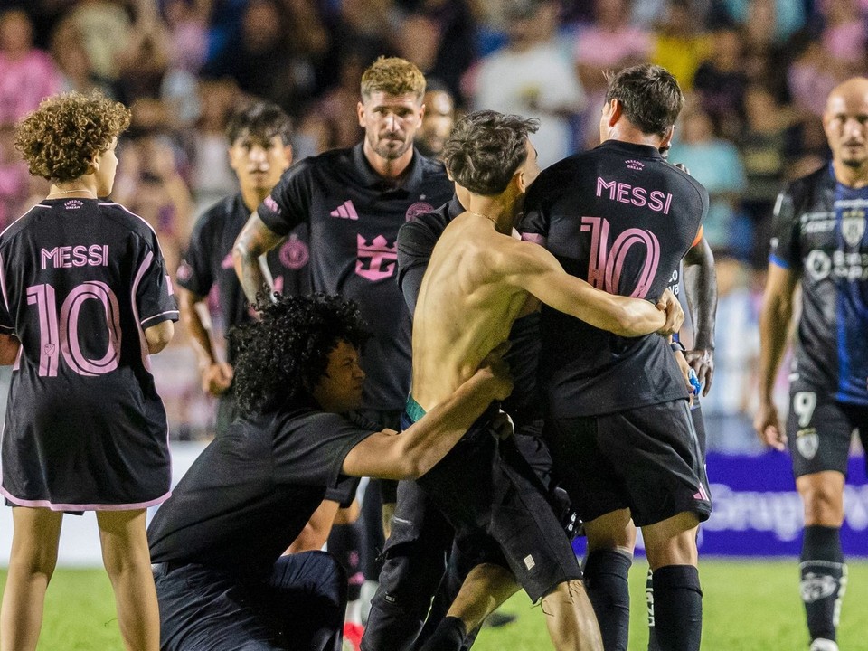 Fanúšik, ktorý sa dostal na ihrisko, chytá hráča Lionela Messiho z Interu Miami na konci prípravného futbalového zápasu.
