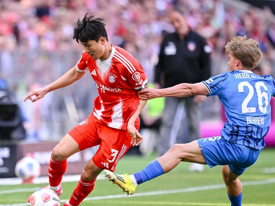 Futbalista Bayernu Kim Min-če (vľavo) a hráč Heidenheimu Hennes Behrens bojujú o loptu.