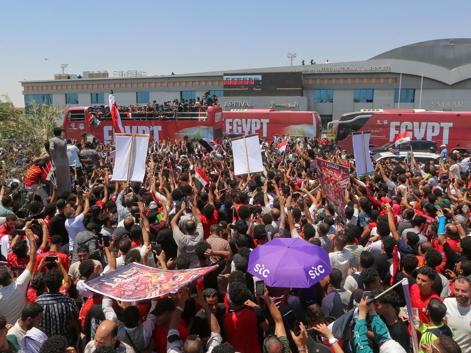 Fanúšikovia vítajú egyptskú futbalovú reprezentáciu po jej prílete na letisko El Alamein.