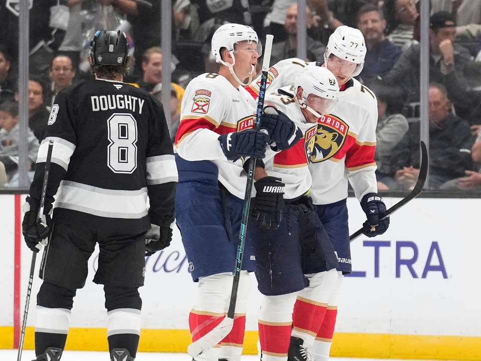 Ľavé krídlo tímu Florida Panthers Brad Marchand (druhý sprava) je po zranení odprevádzaný z ľadu ľavým krídelníkom Bradym Tkachukom (druhý zľava) a obrancom Nikom Mikkolom.