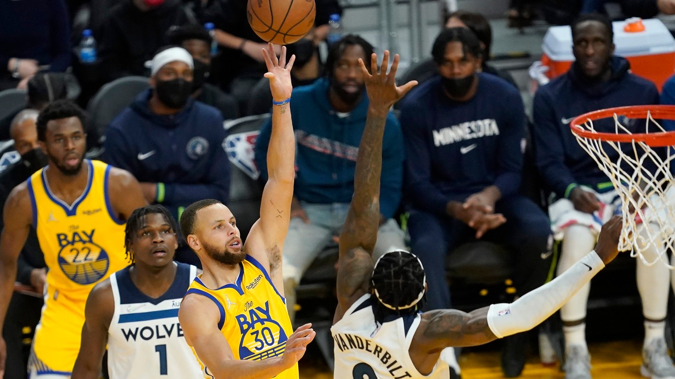 Rozohrávač Golden State Warriors Stephen Curry strieľa medzi hráčmi Minnesota Timberwolves: Anthony Edwards (1) a Jarred Vanderbilt (8).