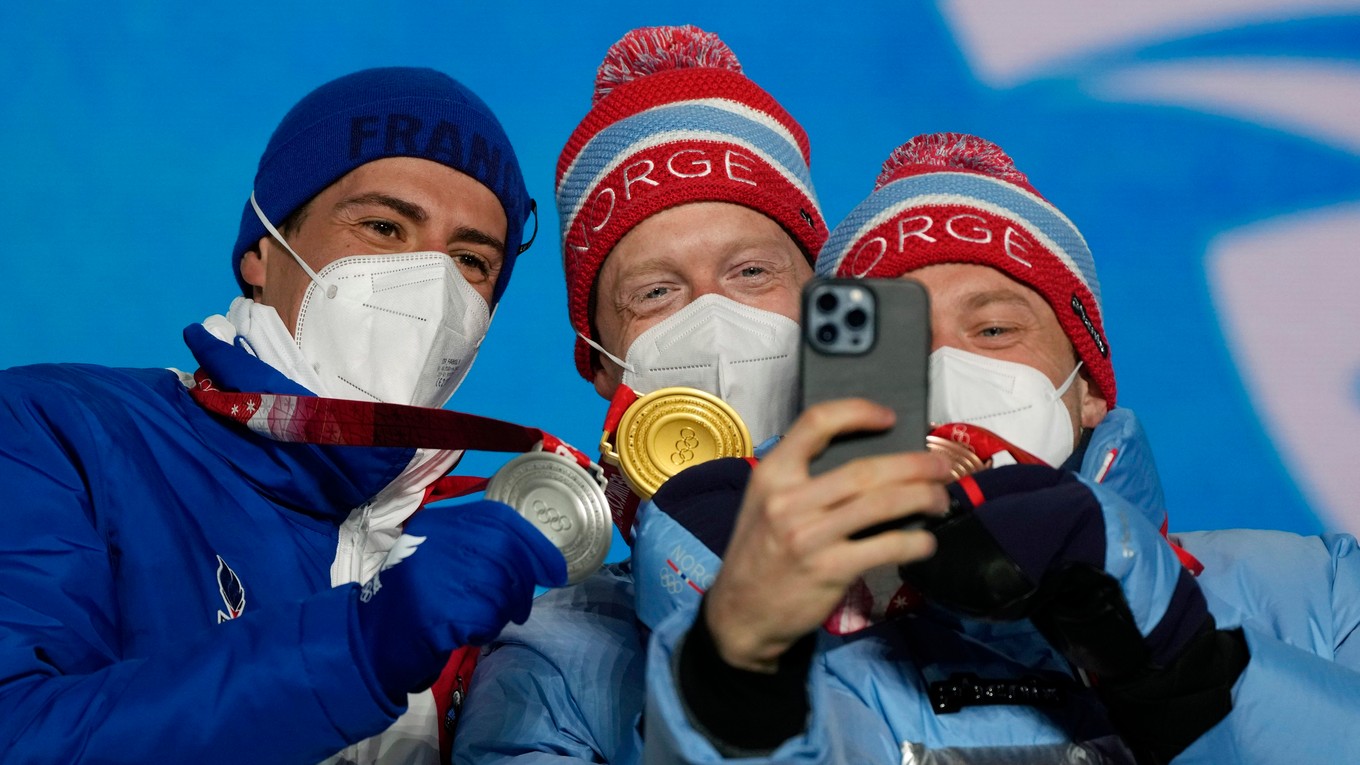 Nórsky biatlonista Johannes Thingnes Bö sa teší na pódiu zo zisku zlatej olympijskej medaily v šprinte mužov na 10 km. Druhý skončil Francúz Quentin Fillon Maillet (vľavo), tretí Tarjei Bö (vpravo).