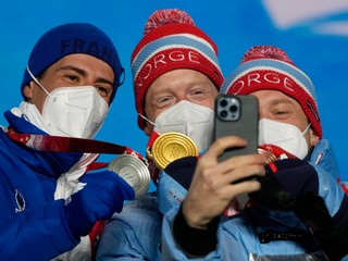 Nórsky biatlonista Johannes Thingnes Bö sa teší na pódiu zo zisku zlatej olympijskej medaily v šprinte mužov na 10 km. Druhý skončil Francúz Quentin Fillon Maillet (vľavo), tretí Tarjei Bö (vpravo).