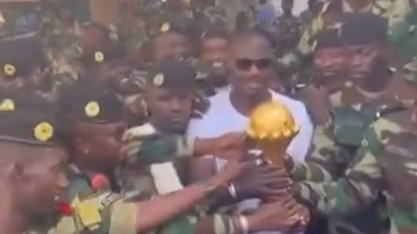 Tréner Senegalu s trofejou medzi vojakmi.