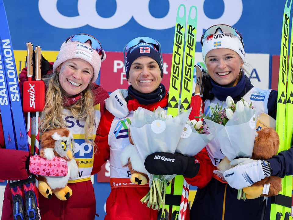 Víťazná nórska bežkyňa na lyžiach Heidi Wengová (uprostred) pózuje na pódiu s druhou Američankou Jessicou Digginsovou (vľavo) a treťou Švédkou Fridou Karlssonovou (vpravo).