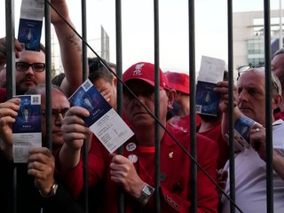 Fanúšikovia Liverpoolu ukazujú lístky a čakajú na vstup na štadión.