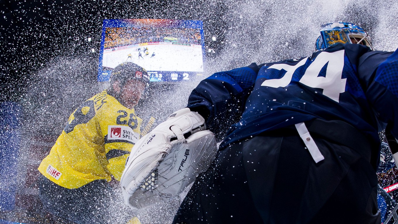 Elias Lindholm zo Švédska a brankár Fínska Juuse Saros v zápase MS 2025 v hokeji.