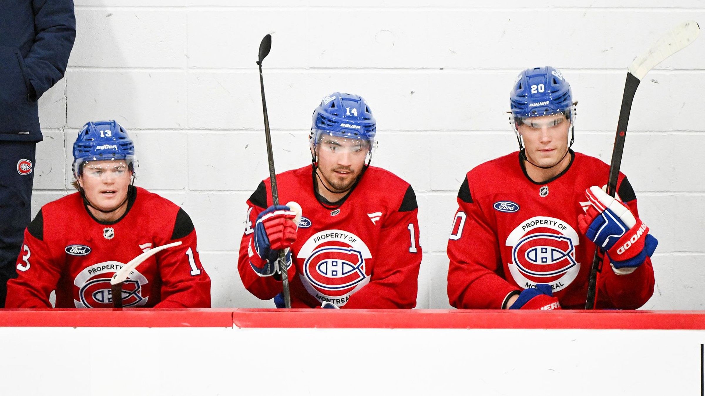 Juraj Slafkovský (vpravo) a jeho spoluhráči Nick Suzuki (uprostred) a Cole Caufield sedia na striedačke počas tréningového zápasu.