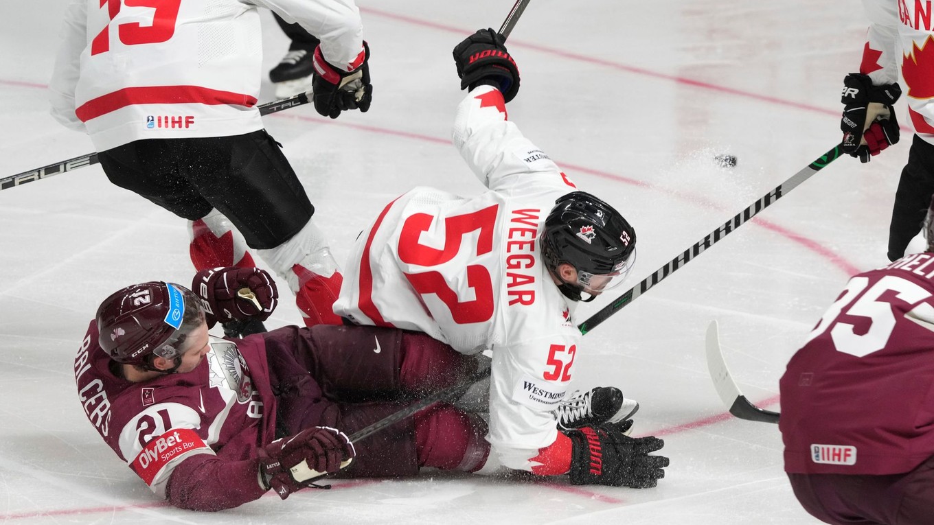 Lotyšský hokejista Rudolfs Balcers v súboji s Kanaďanom Mackenzie Weegerom. 