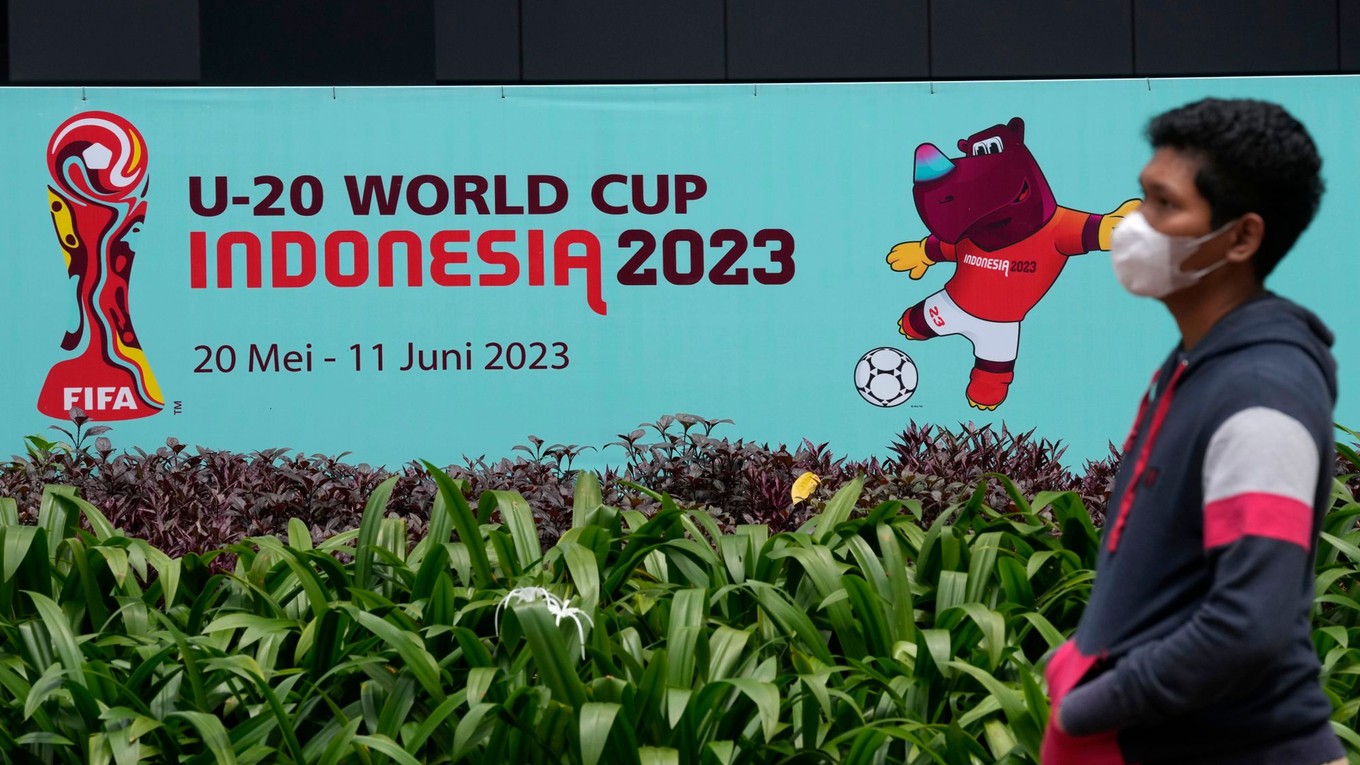 Muž kráča okolo reklamného pútača MS do 20 rokov 2023, ktoré mala hostiť Indonézia. 
