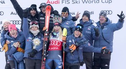 Mikaela Shiffrinová sa raduje na pódiu so svojím tímom z víťazstva v slalome v Jasnej. Asistent trénerky Mark Mitter je druhý zľava (horný rad). 