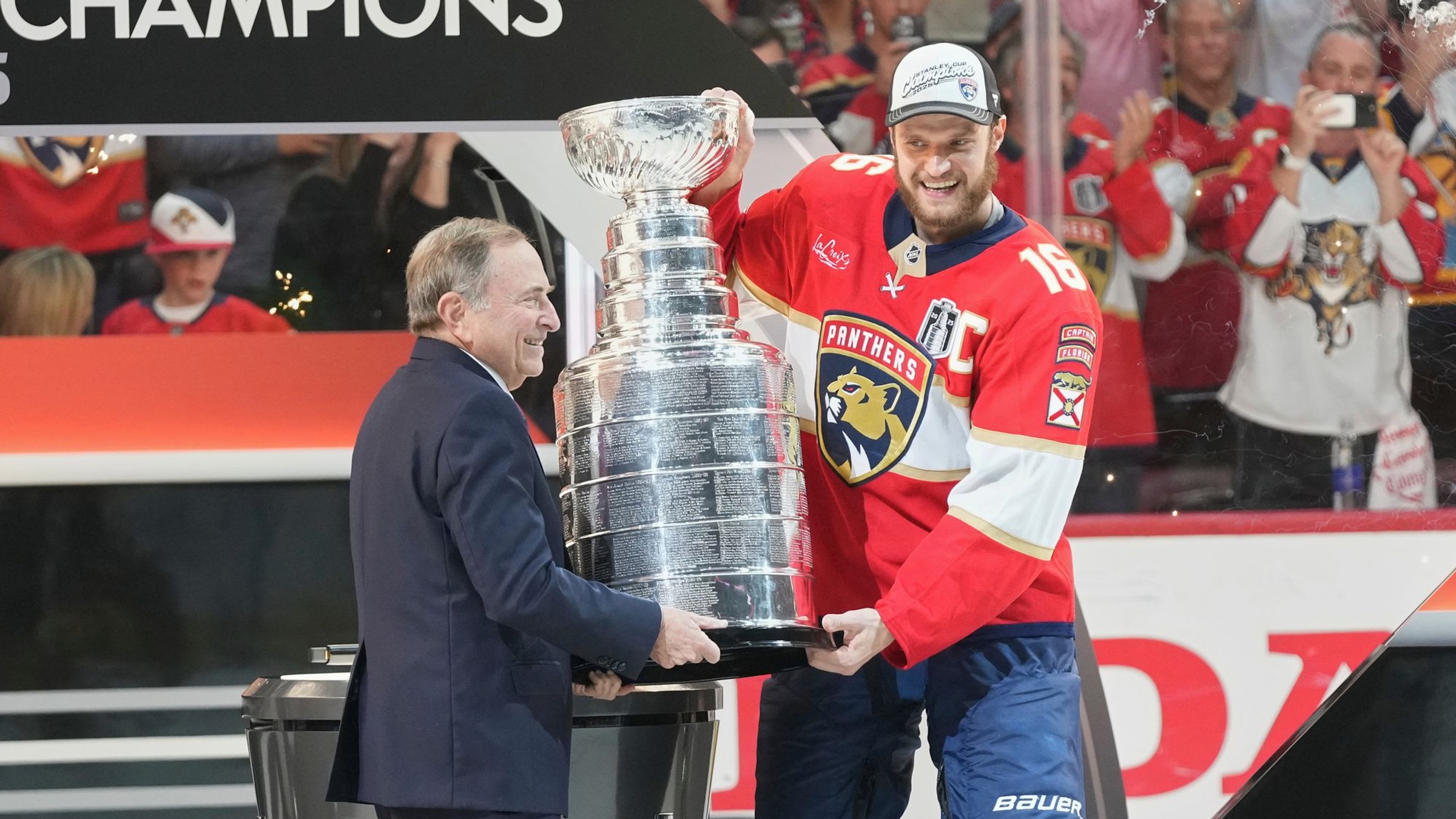Kapitán Floridy Aleksander Barkov (vpravo) a komisár hokejovej NHL Gary Bettman držia Stanleyho pohár.