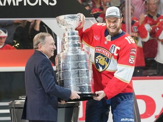 Kapitán Floridy Aleksander Barkov (vpravo) a komisár hokejovej NHL Gary Bettman držia Stanleyho pohár.