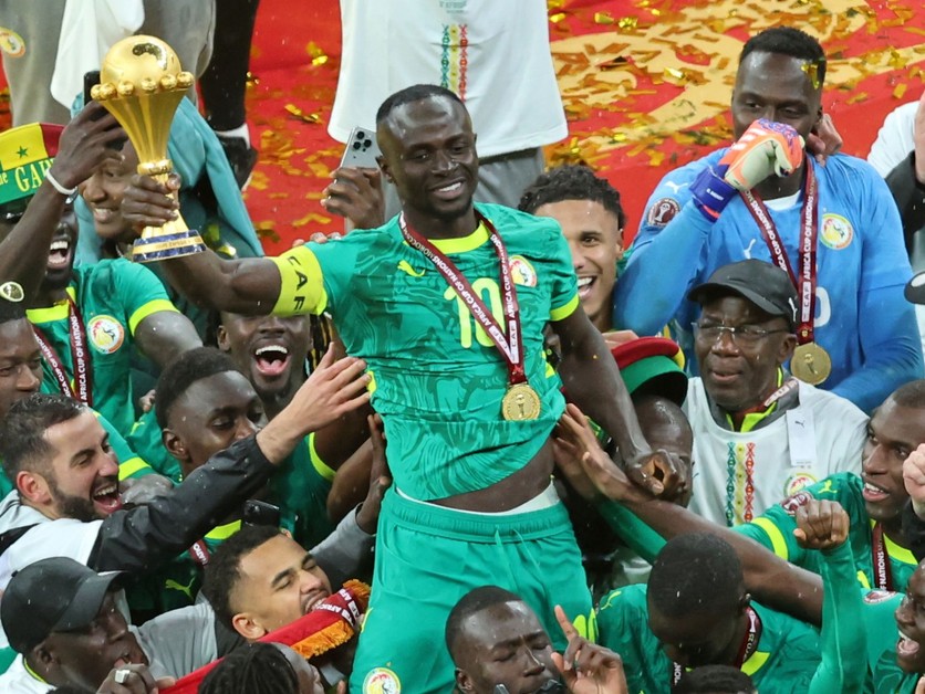 Sadio Mané zo Senegalu drží trofej nad hlavou a oslavuje so spoluhráčmi po víťazstve vo finále.