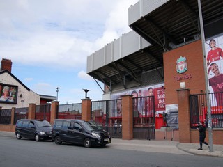 Na snímke vľavo transparent s podobizňou zosnulej britskej královnej Alžbety II. je umiestnený na jej pamiatku vedľa štadiónu Anfield, na ktorom hráva svoje domáce zápasy FC Liverpool.